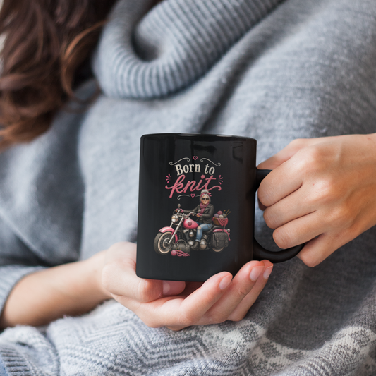 Woman holding a mug with a design, wearing a gray sweater and glasses.