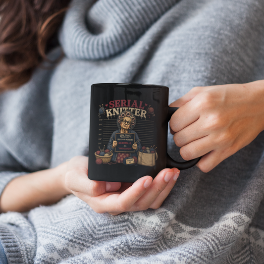 Woman holding a black mug with a Batman logo, wearing a gray sweater.